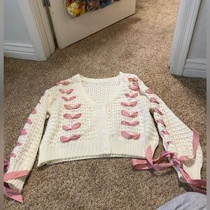White cardigan with pink ribbon